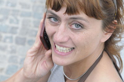 Close-up portrait of smiling young woman using mobile phone