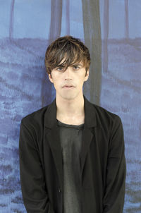 Portrait of young man standing against wall