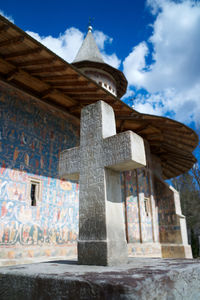 Low angle view of cross on building against sky