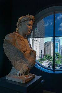 Statue by buildings against sky in city