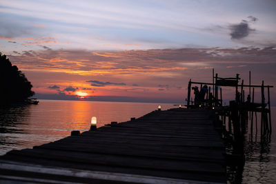 Pier over sea against sky during sunset