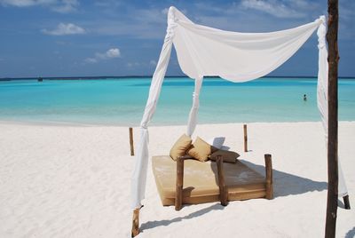 Scenic view of mattress on beach against cloudy sky