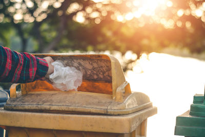 Cropped hand of person throwing garbage in bin