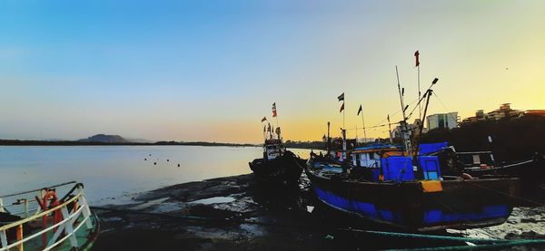 Sailboats moored in sea against sky during sunset