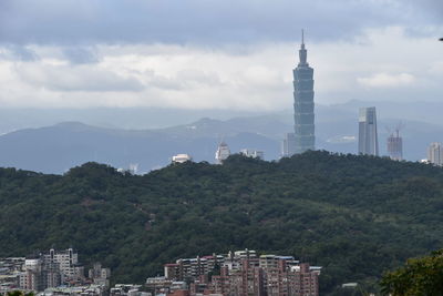 Buildings in city against cloudy sky