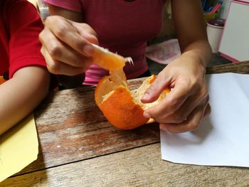 Close-up of woman peeling mandarins on table