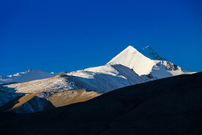 Built structure on snowcapped mountain against clear blue sky