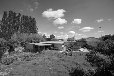 Houses on field by buildings against sky