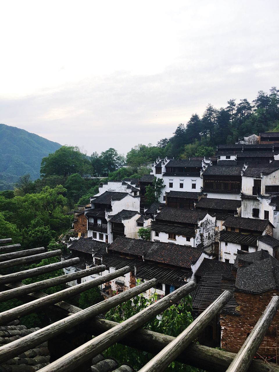 building exterior, architecture, built structure, high angle view, tree, sky, house, roof, residential structure, residential building, mountain, cloud - sky, residential district, railroad track, town, day, city, townscape, cityscape, outdoors