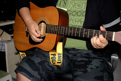 Midsection of man playing guitar