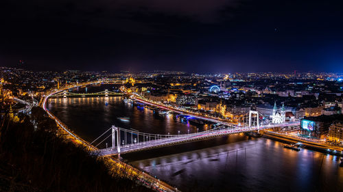 Illuminated bridge over river at night