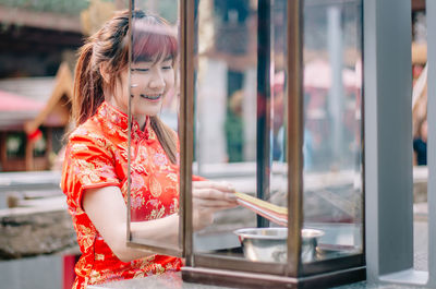 Young woman in traditional clothing burning incense