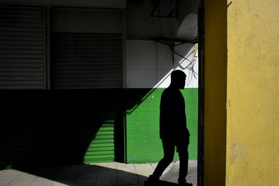 Silhouette woman with umbrella walking in corridor of building