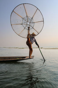 Man fishing in sea against sky