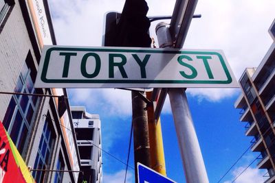 Low angle view of sign board against cloudy sky