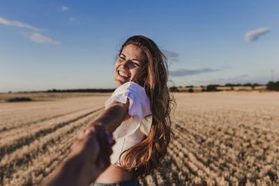 Cropped image of boyfriend holding girlfriend hand on agricultural field