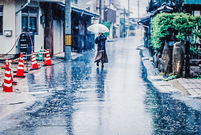 Full length of wet man walking in city during rainy season