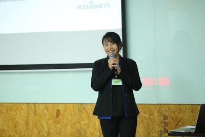 Portrait of smiling businesswoman holding microphone while standing against projection screen