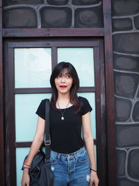 Smiling young woman standing against wall