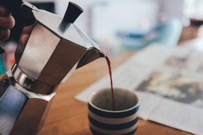 Close-up of coffee pouring in cup on table at home