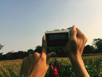 Man photographing on field against clear sky