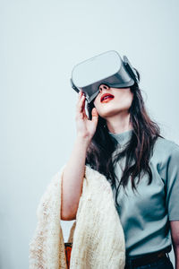 Young woman using virtual reality simulator against white background