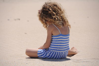 Rear view of girl on sand at beach