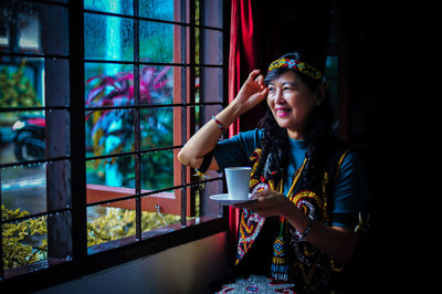 Side view of young woman looking through window