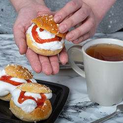 A caucasian female preparing traditional finnish shrove buns with whipped cream filling.