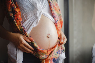 Midsection of pregnant woman standing at home