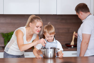 Kind caucasian parents teaching their little adorable son how to cook healthy