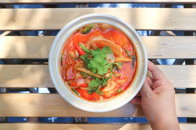 Cropped image of person holding soup in bowl on table