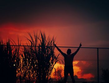 Silhouette man standing against orange sky during sunset