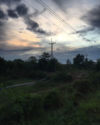 Electricity pylon on landscape against sky during sunset