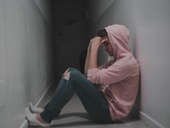Side view of senior woman sitting against wall at home