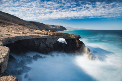 Scenic view of rocks in sea against sky