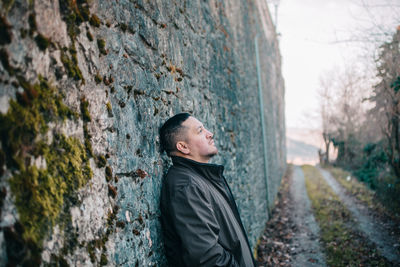 Thoughtful man standing by wall