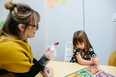 Teacher holds a spoonful of food to feed to student and student pouts