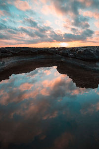 Scenic view of lake against dramatic sky during sunset