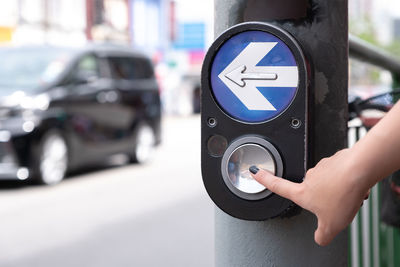 Cropped hand of woman pushing button in city