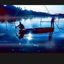 Man in boat on lake against sky during sunset