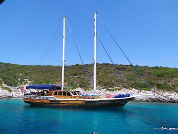 Sailboats moored in sea against clear blue sky