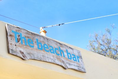 Low angle view of signboard against blue sky