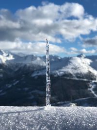 Icicles on snow covered land against sky