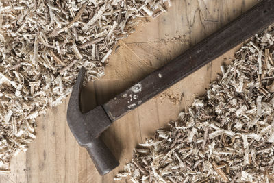 Directly above shot of hammer amidst sawdust on wooden table