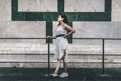 Full length of woman standing against wall