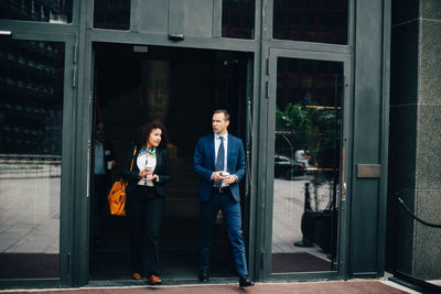 Full length of multi-ethnic business colleagues walking through doorway