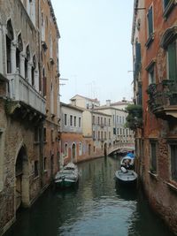 Canal amidst buildings in city against sky