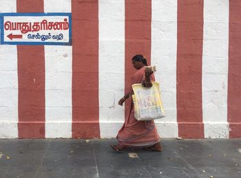 Rear view of woman standing against wall