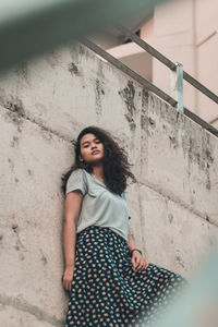 Portrait of smiling woman standing against wall